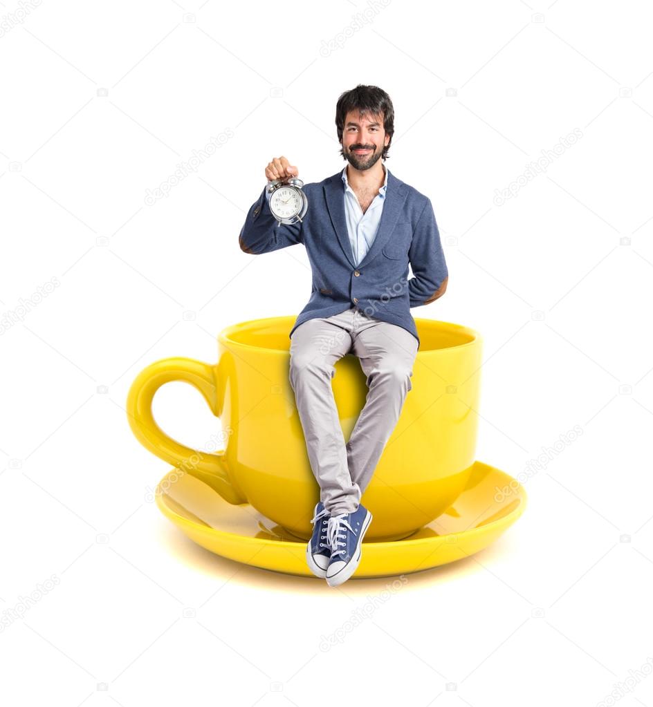 Man holding a clock on cup of coffee