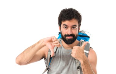 Backpacker making a good-bad sign over white background