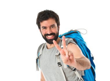 Beyaz arka plan üzerinde zafer jest yapıyor backpacker