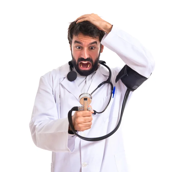 Frustrierter Arzt mit Blutdruckmessgerät vor weißem Hintergrund — Stockfoto