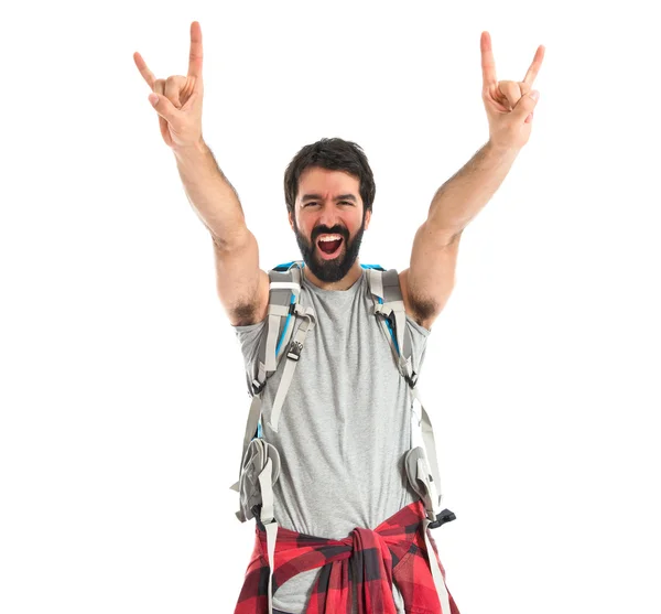 Backpacker making horn gesture over white background — Stockfoto