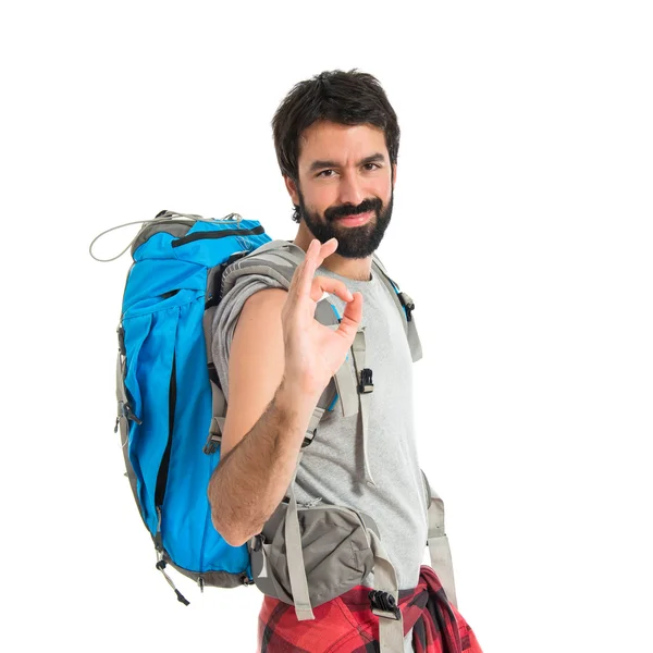 Backpacker making Ok sign over white background — стоковое фото