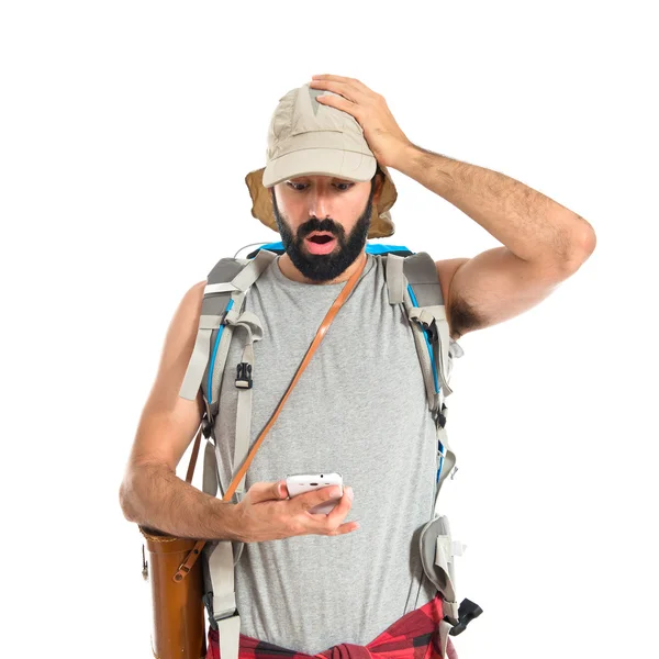 Überraschter Backpacker spricht mit Handy über weißem Hintergrund — Stockfoto