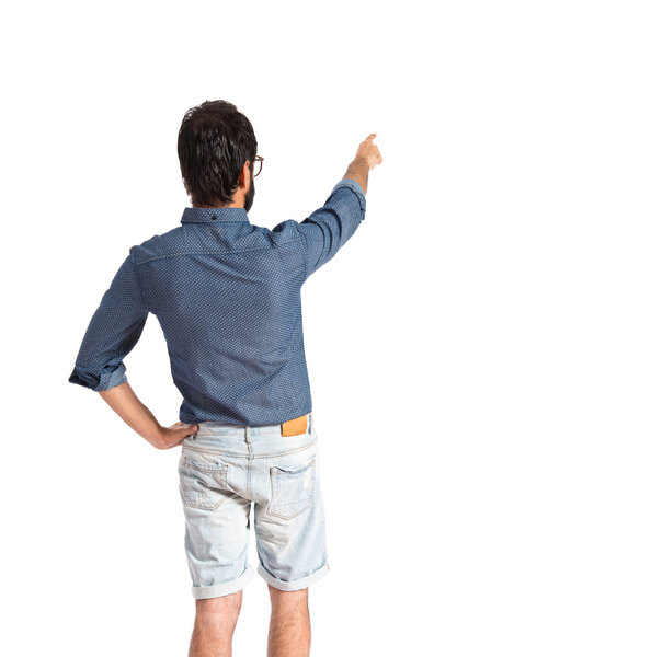 Young hipster man pointing back over white background  