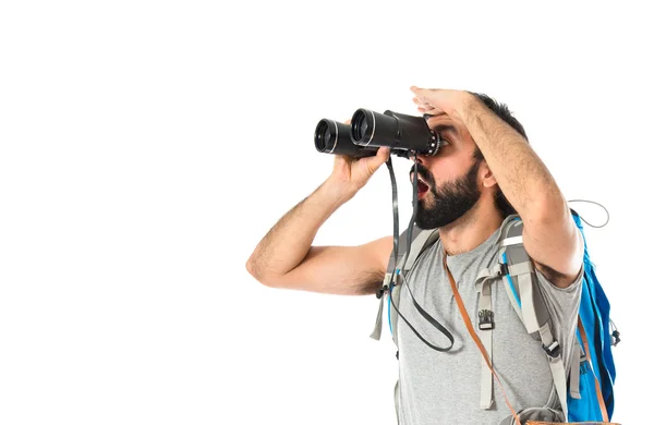 Backpacker with binoculars over isolated white background — Stock Photo, Image