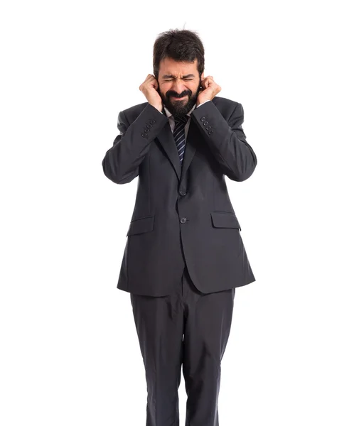 Empresario cubriéndose las orejas sobre fondo blanco — Foto de Stock