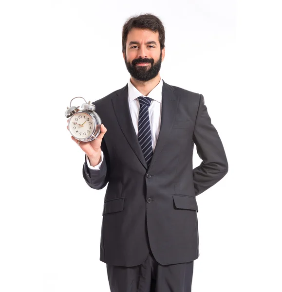 Businessman holding a clock over white background — Stock Photo, Image