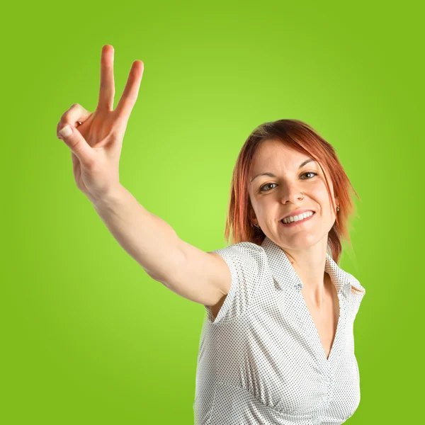 Young woman doing victory gesture over green background — Stock Photo, Image