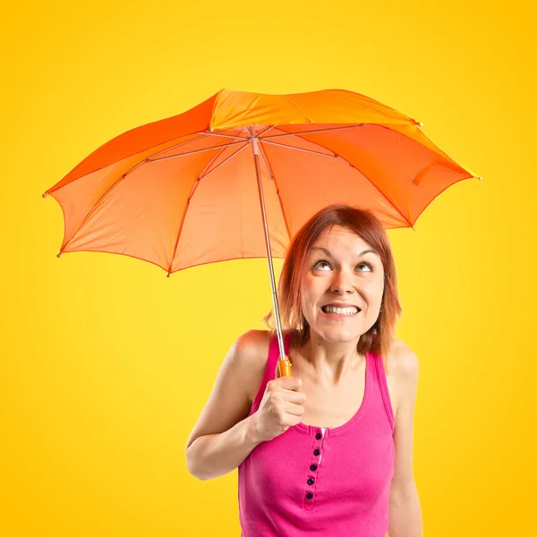 Ragazza che tiene un ombrello su sfondo giallo — Foto Stock