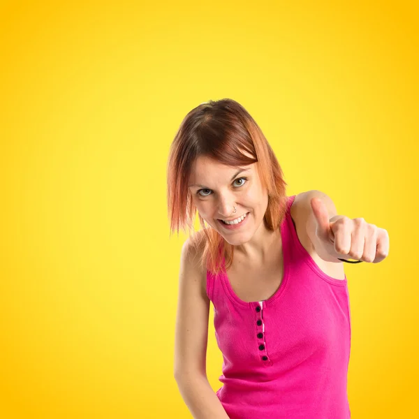 Menina bonita com polegares para cima sobre fundo amarelo — Fotografia de Stock