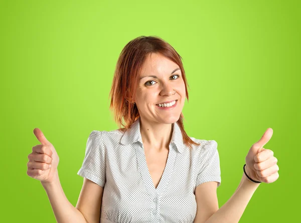 Pretty young girl with thumbs up over green background — Stock Photo, Image