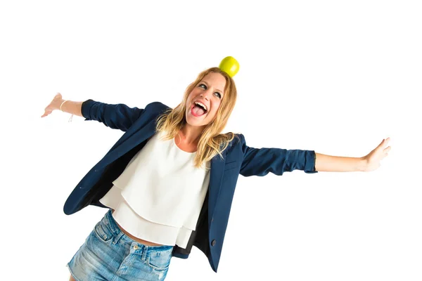 Blonde girl with apple above her head over white background — Stock Photo, Image