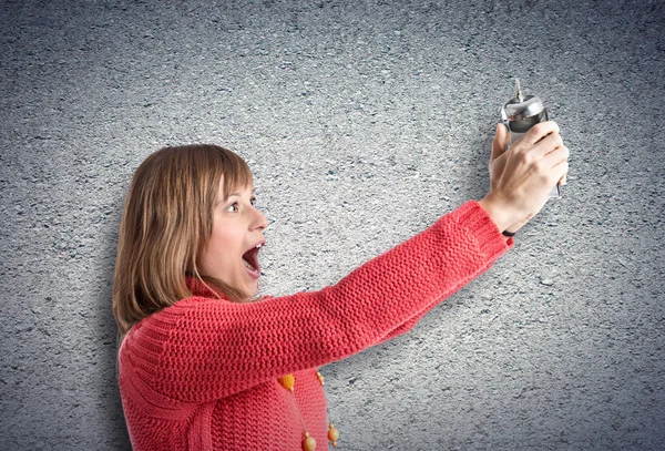 Girl holding a clock over textured background — Stock Photo, Image