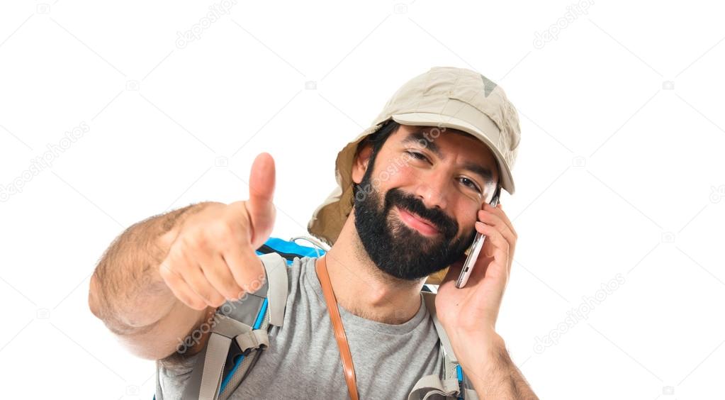 Backpacker talking to mobile over white background