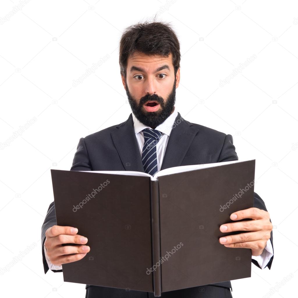 Surprised businessman reading a book over white background