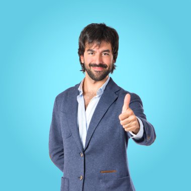 Mavi arka plan üzerinde başparmak ile yakışıklı adam  