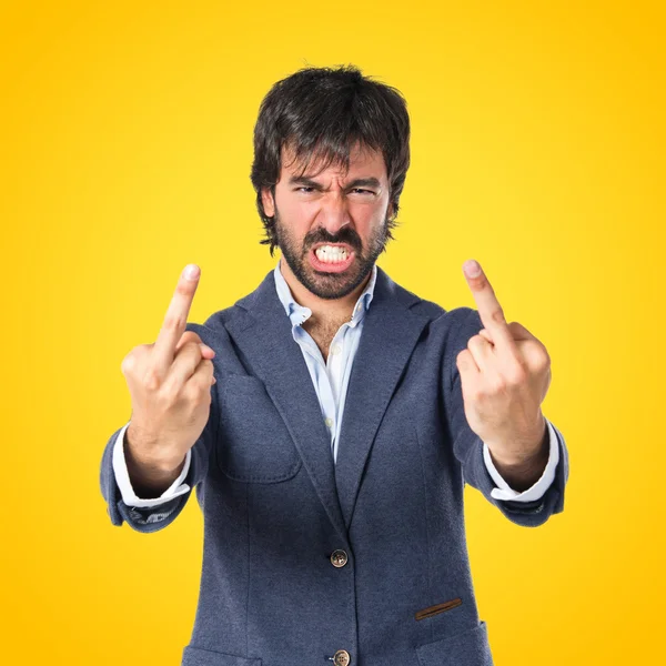 Affärsman gör horn gest över gul bakgrund — Stockfoto