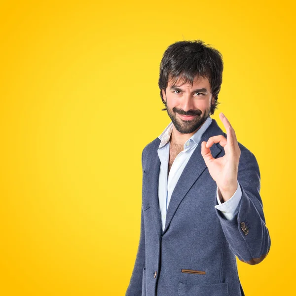 Geschäftsmann macht ok Zeichen über gelbem Hintergrund — Stockfoto