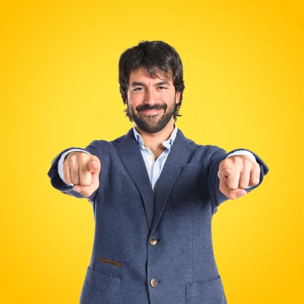 Businessman pointing to the front over yellow background — Stock Photo, Image