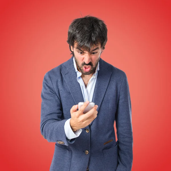 Hombre enojado hablando con móvil sobre fondo rojo —  Fotos de Stock