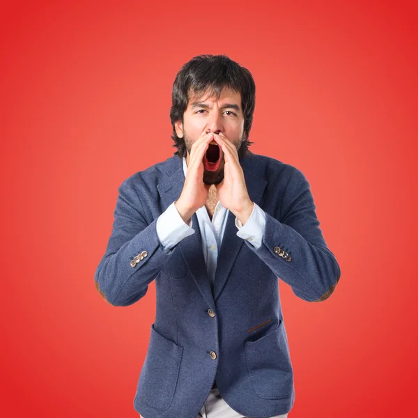 Handsome man shouting over red background — Stock Photo, Image