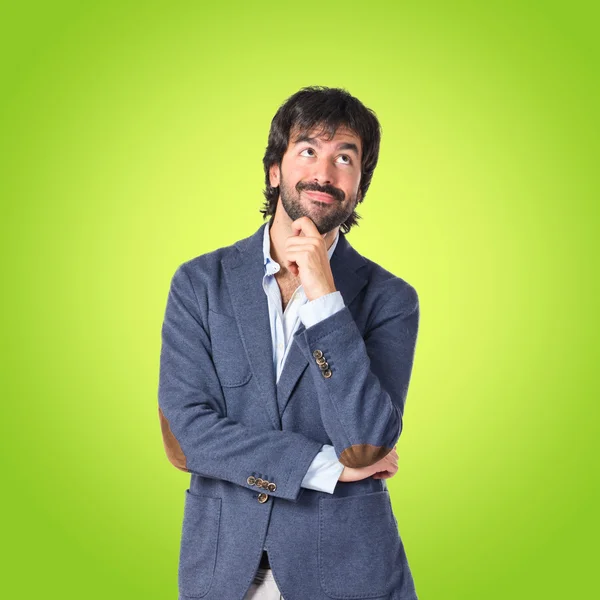 Businessman thinking over green background — Stock Photo, Image