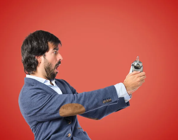 Man holding a clock over red background — Stock Photo, Image