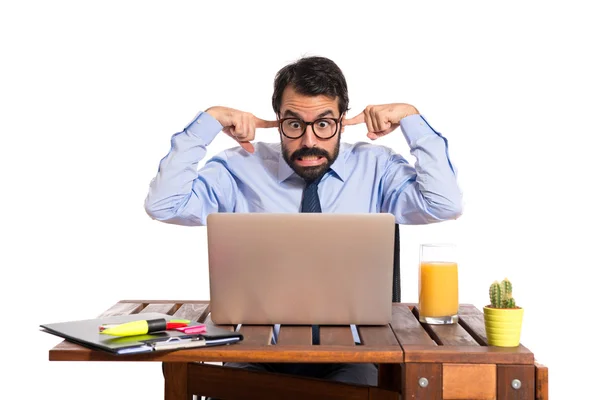 Businessman in his office covering his ears — Stock Photo, Image