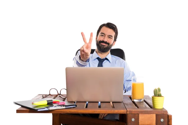 Businessman in his office doing victory gesture — Stock Photo, Image