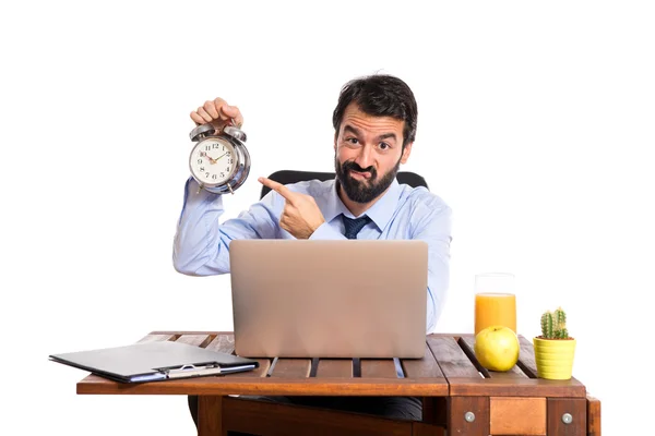 Empresário em seu escritório segurando um relógio — Fotografia de Stock