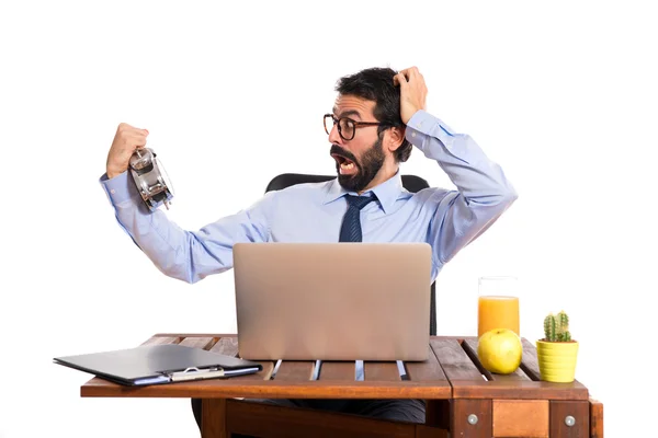 Verrast zakenman in zijn kantoor houden een klok — Stockfoto