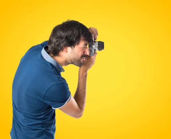 Hombre fotografiando sobre fondo amarillo — Foto de Stock