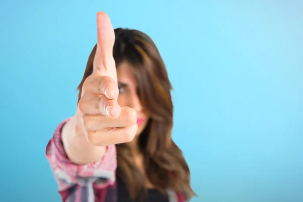 Chica joven haciendo gesto pistola sobre fondo azul —  Fotos de Stock