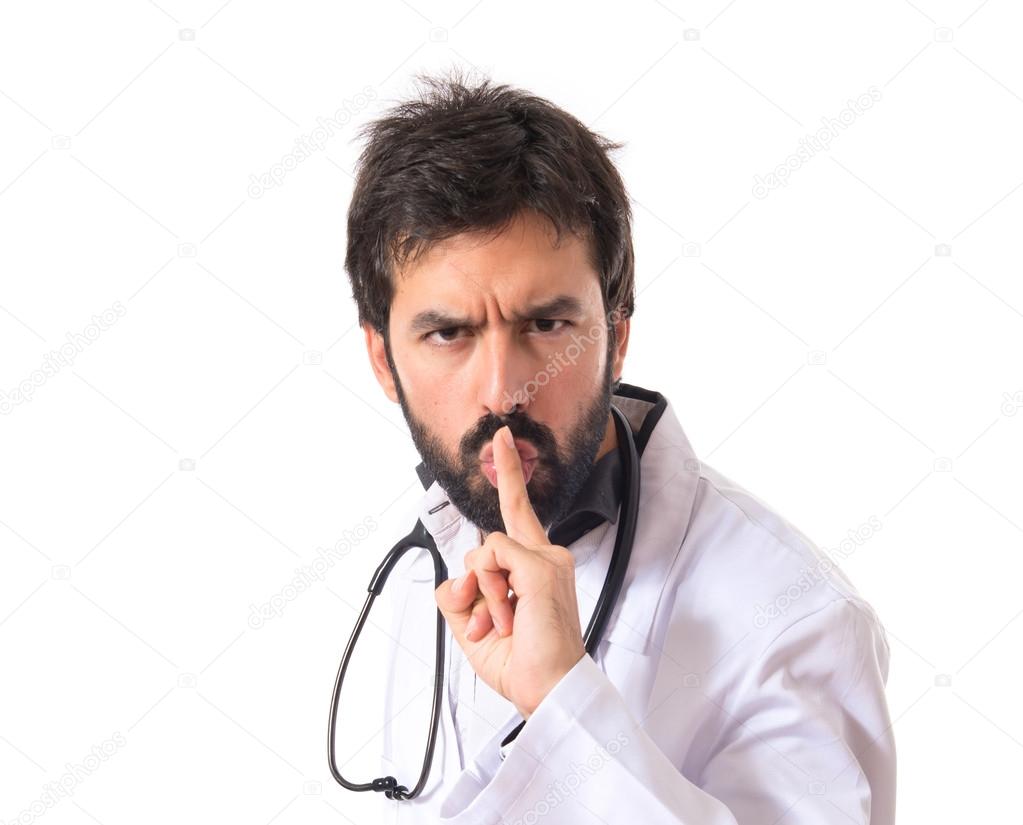 Doctor making silence gesture over isolated white background