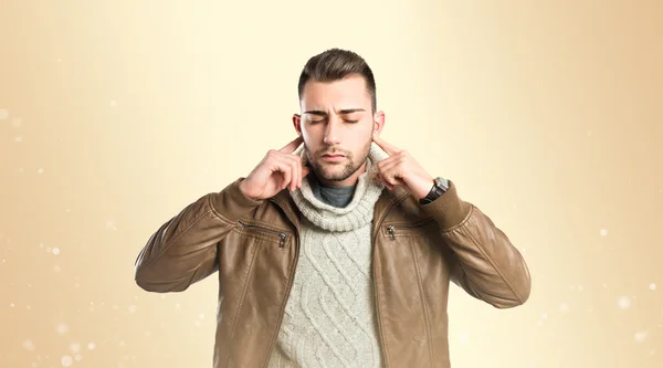 Hombre cubriéndose las orejas sobre fondo ocre — Foto de Stock