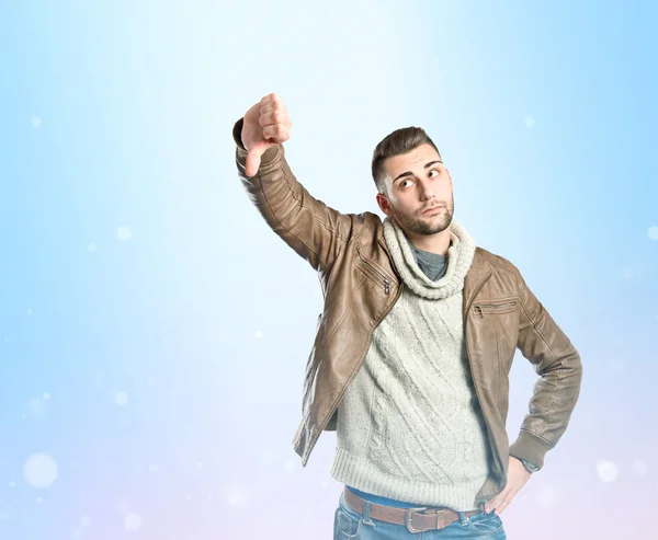 Man doing a bad signal over blue background — Stock Photo, Image