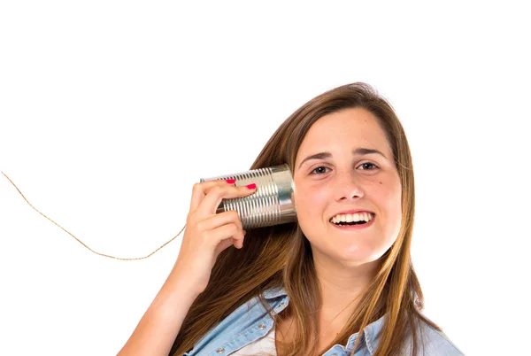 Menina ouvindo através de um telefone estanho sobre fundo branco — Fotografia de Stock