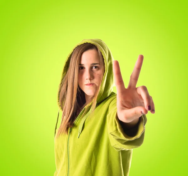 Girl doing victory gesture over green background — Stock Photo, Image