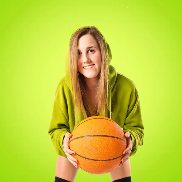 Menina loira jogando basquete sobre fundo verde — Fotografia de Stock