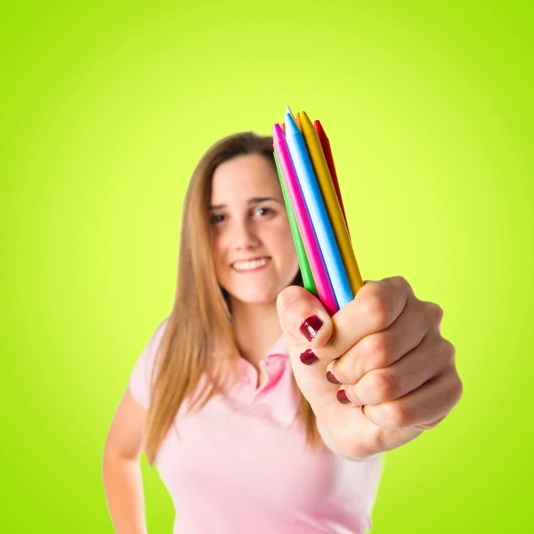 Chica rubia sosteniendo lápices de colores sobre fondo verde —  Fotos de Stock