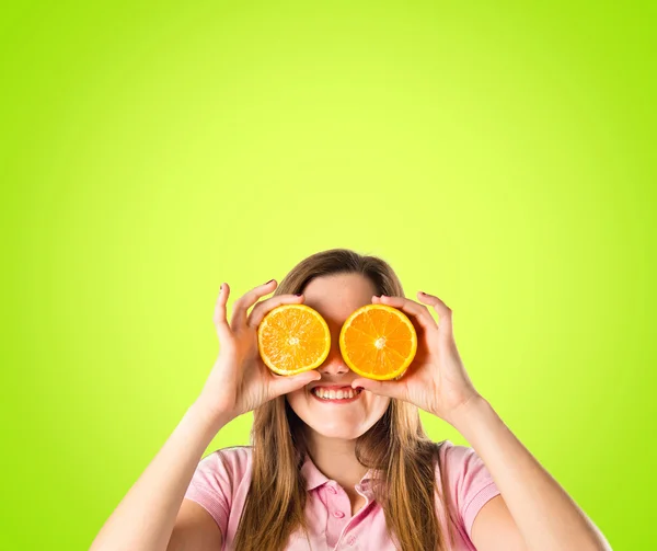 Mädchen mit Orangen in den Augen vor grünem Hintergrund — Stockfoto