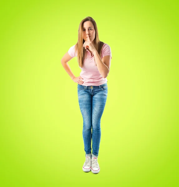 Молодая девушка делает жест молчания на зеленом фоне — стоковое фото