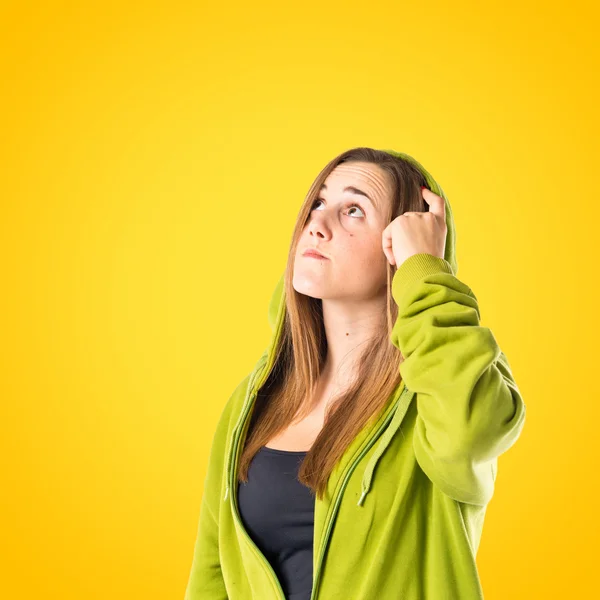 Chica joven pensando sobre fondo amarillo — Foto de Stock