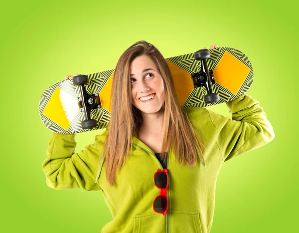 Skater with green sweatshirt over green background — Stock Photo, Image