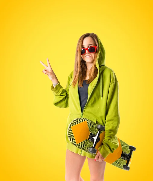 Young girl doing victory gesture over yellow background — Stock Photo, Image