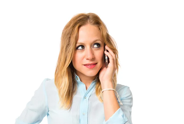 Blonde girl talking to mobile over white background — Stock Photo, Image