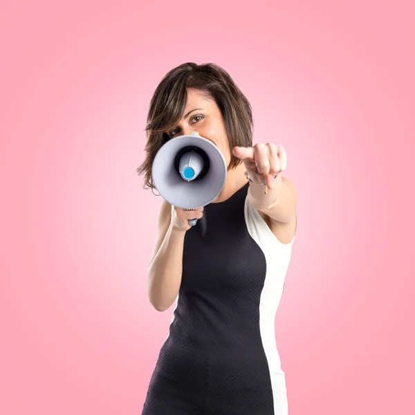 Pretty girl shouting with a megaphone over pink background — Stock Photo, Image