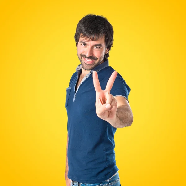 Man doing victory gesture over yellow background — Stock Photo, Image