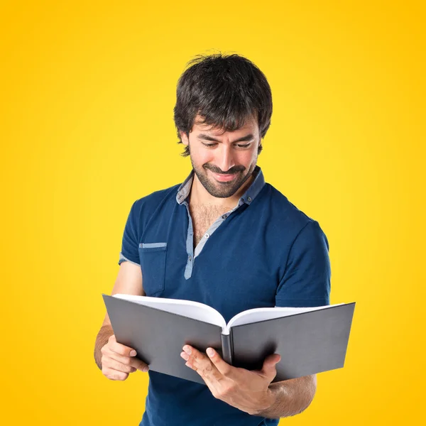 Hombre leyendo un libro sobre fondo amarillo — Foto de Stock