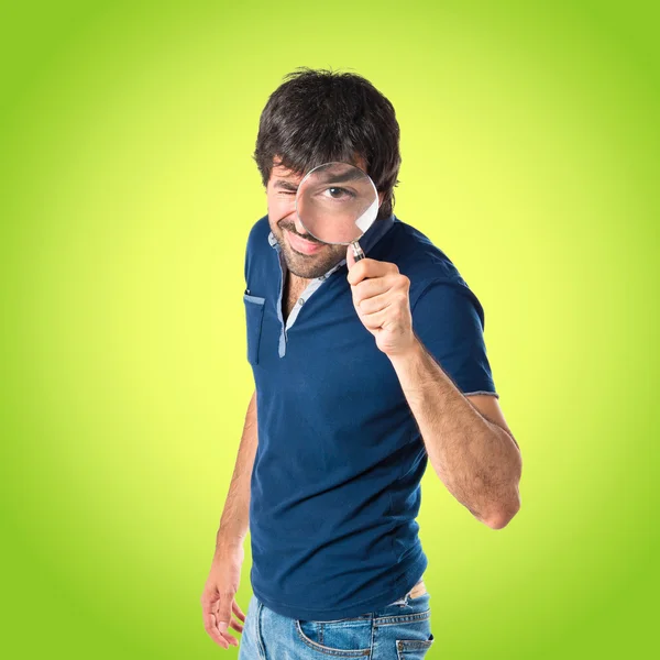 Man with magnifying glass over green background — Stock Photo, Image